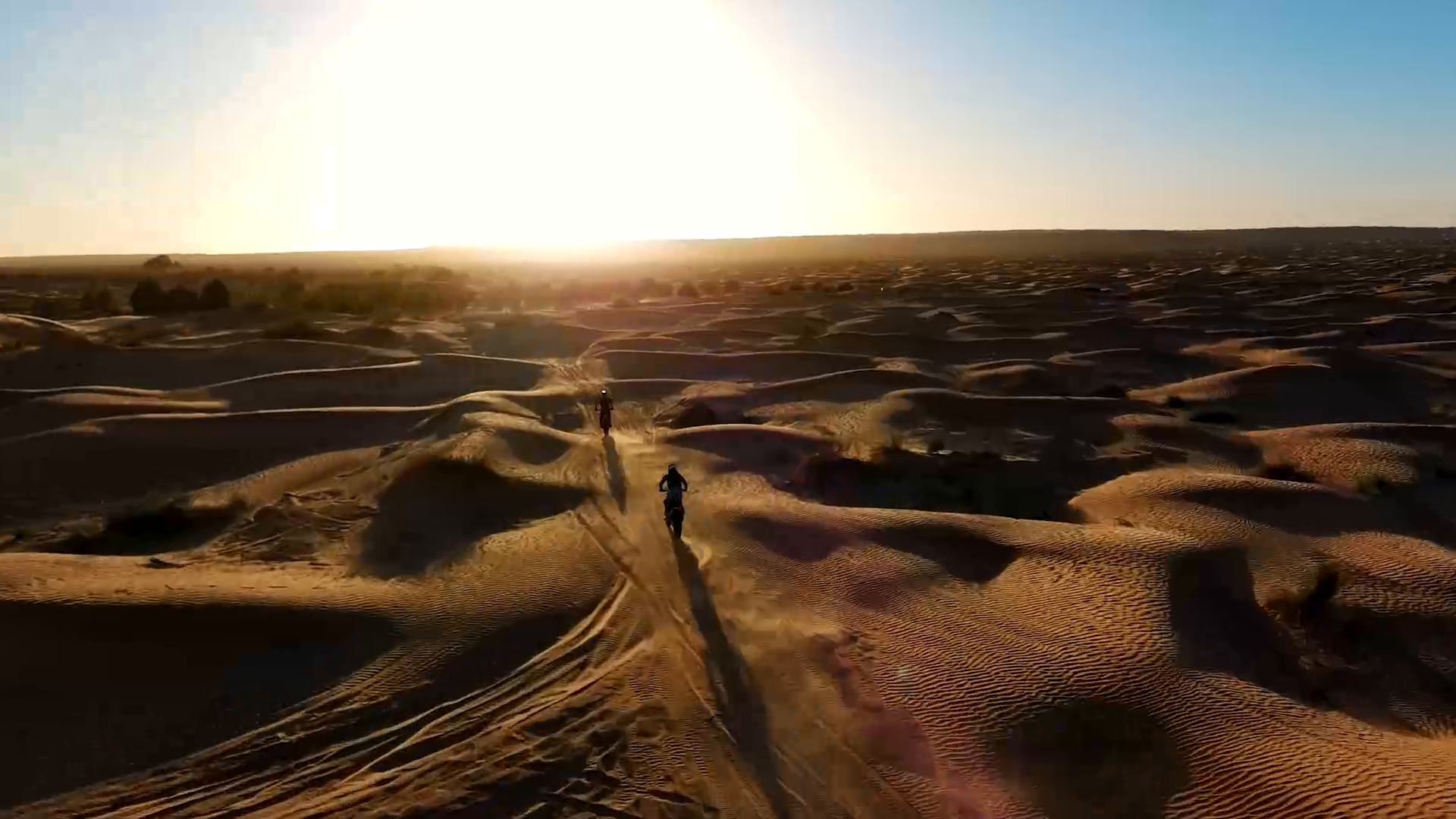 Un pilota attraversa le dune al tramonto, ripreso dall'alto