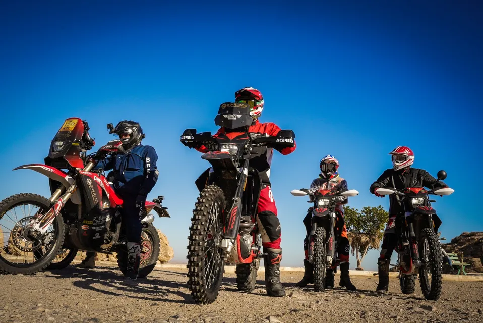 Quattro piloti in sella alle moto sotto un cielo blu intenso