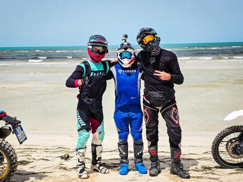 Tre piloti abbracciati sulla spiaggia davanti al mare
