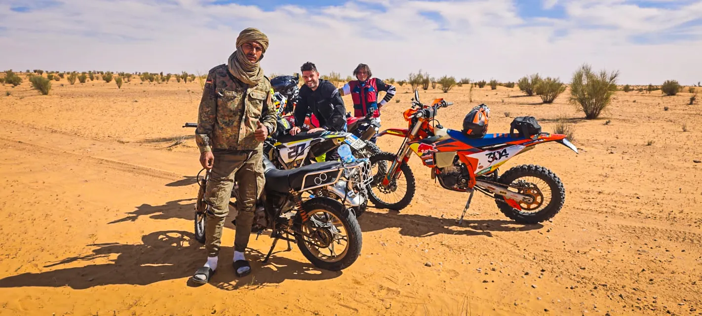 Una guida del deserto in posa con il pollice alzato accanto alle moto