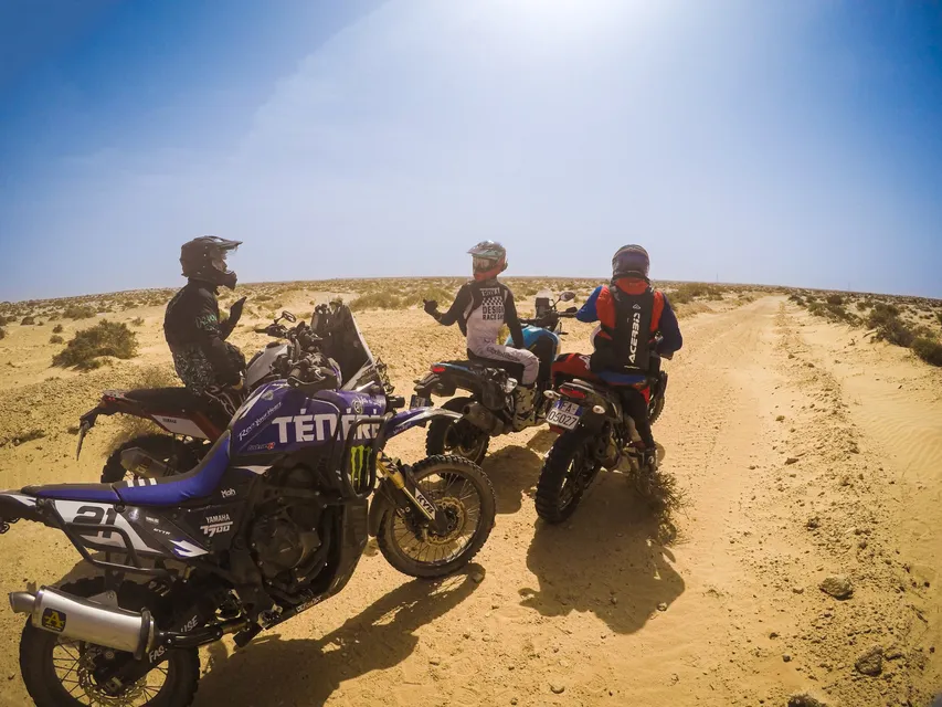 Tre moto ferme su una pista di sabbia, in un'inquadratura grandangolare