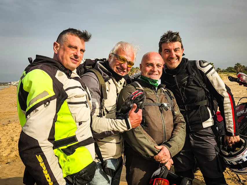 Quattro amici sorridono in posa sulla spiaggia