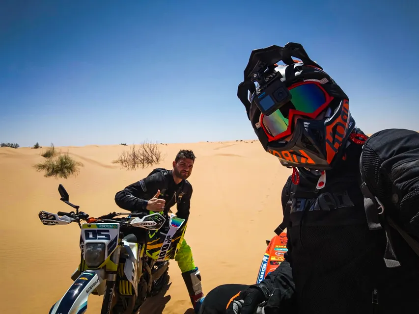 Selfie tra le dune: un pilota con la telecamera sul casco e un amico che fa il pollice alzato